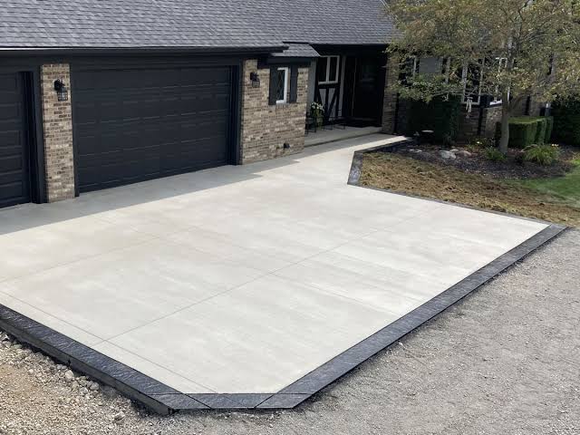 Finished concrete driveway with a contrasting stamped border, running up to a two car garage
