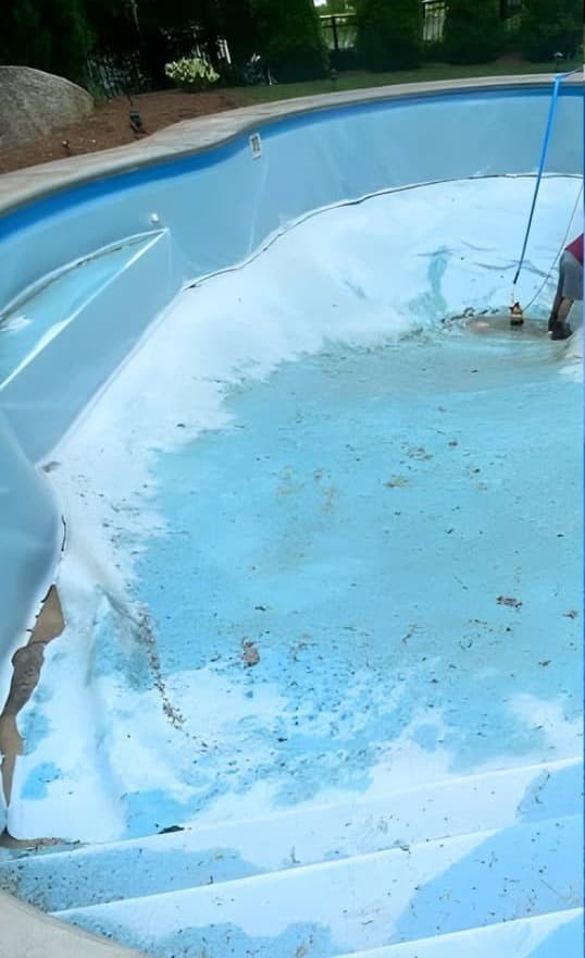 Drained pool with a worn, torn vinyl liner before replacement